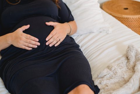 Photo by Amina Filkins; pregnant woman embracing belly