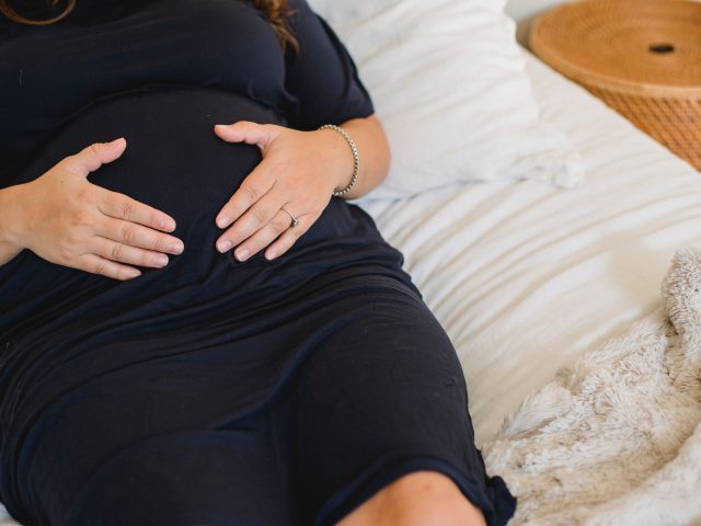 Photo by Amina Filkins; pregnant woman embracing belly